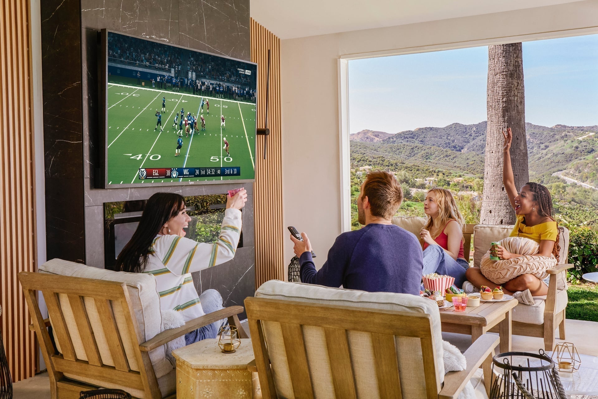 Friends watching NFL game on Sylvox outdoor TV in backyard during Sunday afternoon party