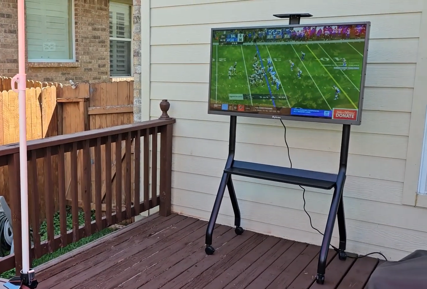 Sylvox Gaming Series Outdoor TV showing NFL game on balcony with IP56 weatherproof protection